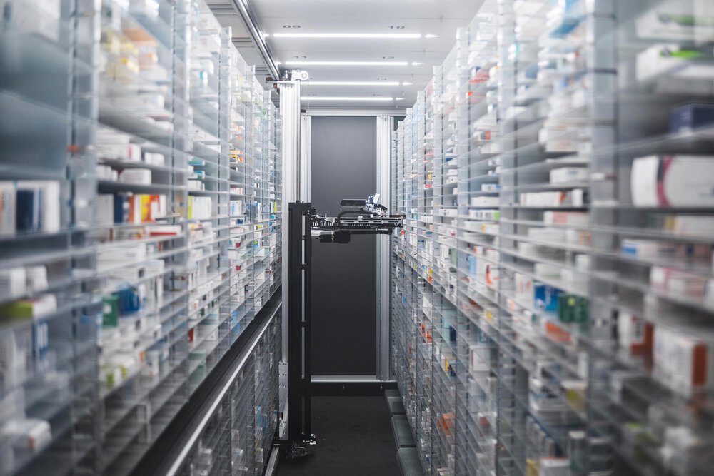 Aisle with high shelves full of medicines with robotic urine that can grab medicines. Symbol photo for life, sciences, pharmaceutical sales, consultant, consulting, mergers, acquisitions, M&A, company sale